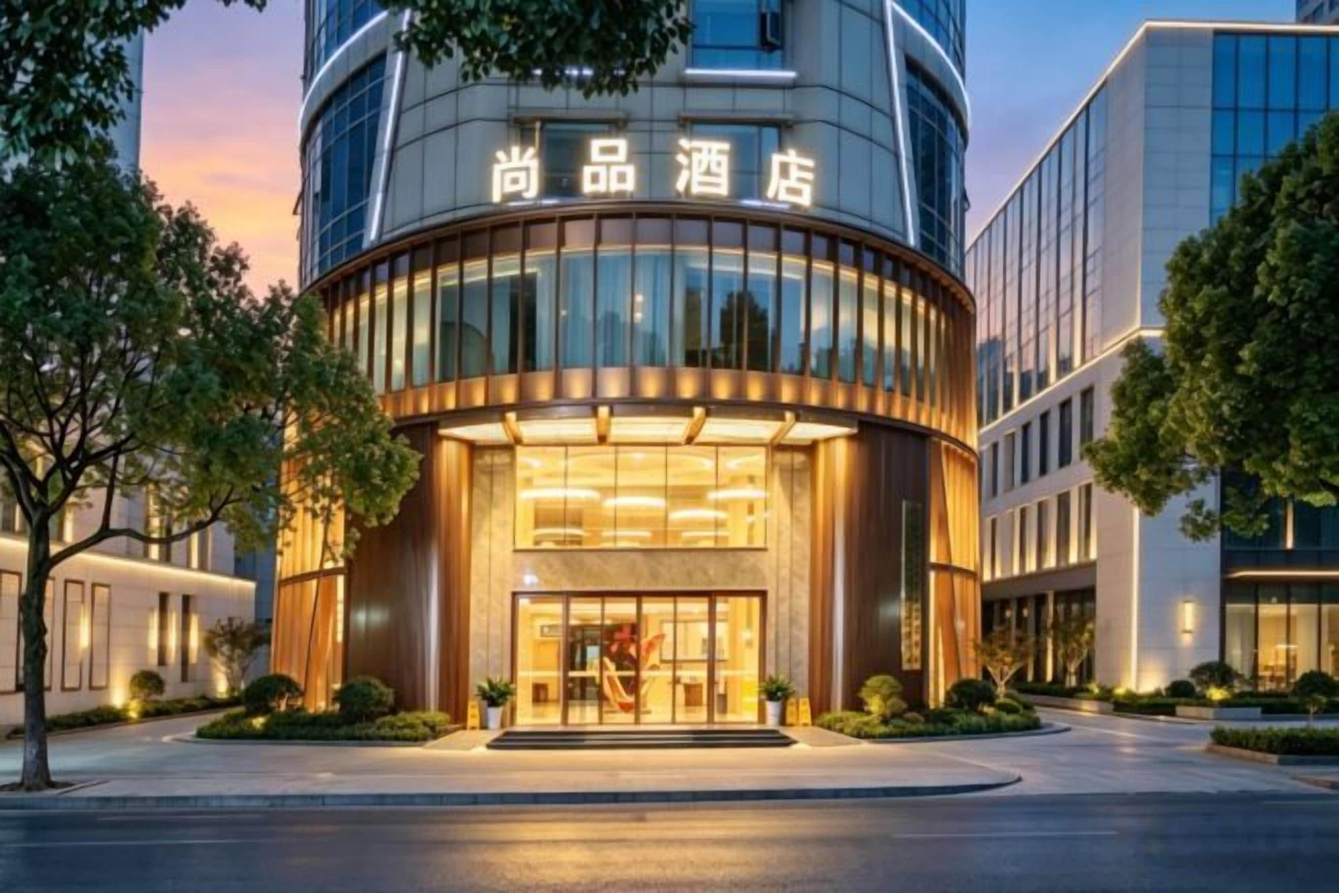 Un hotel con fachada curva, un amplio acceso de vidrio y señalización en un idioma extranjero.