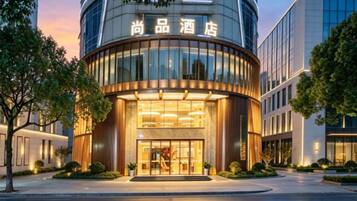 Un hotel con fachada curva, un amplio acceso de vidrio y señalización en un idioma extranjero.