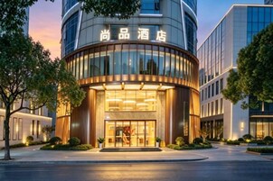Un hotel con fachada curva, un amplio acceso de vidrio y señalización en un idioma extranjero.