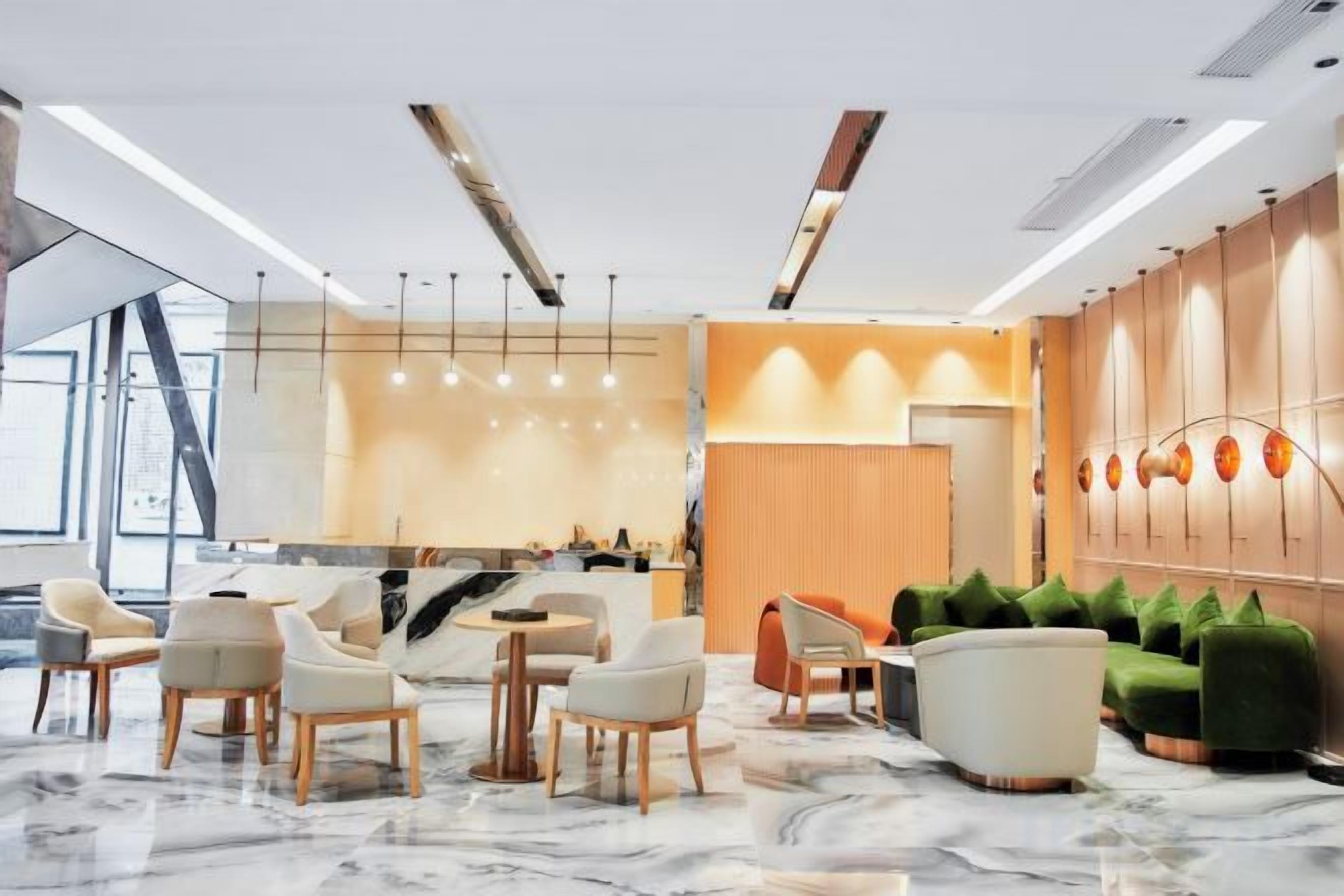A modern hotel lobby with marble flooring, a reception desk, seating area, and a wall with lockers.