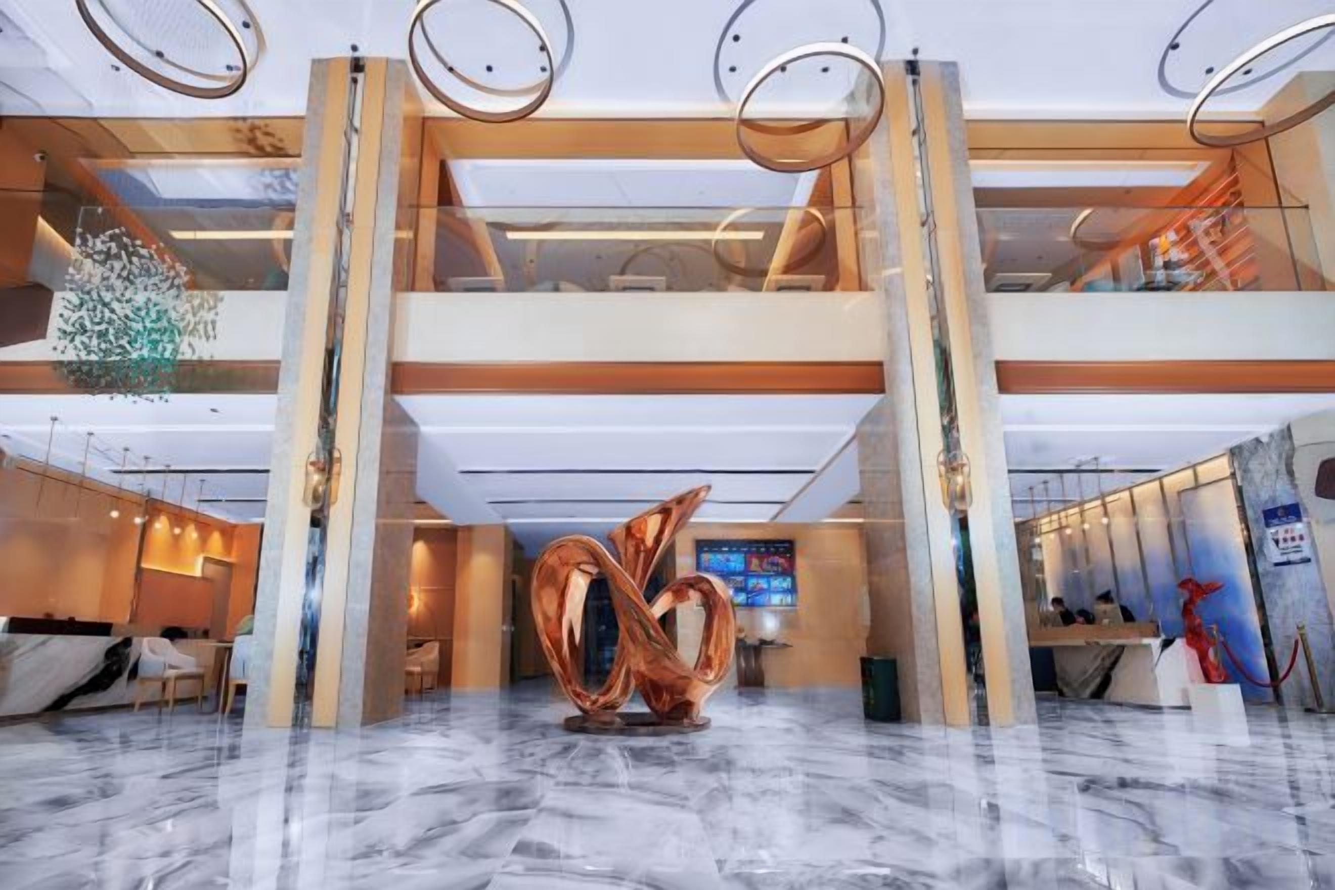 Rebedor d'hotel amb sòl de marbre, una taula d'informació i una gran escultura abstracta.