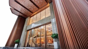 A modern building with a prominent entrance, large glass windows, and a unique facade with vertical wooden slats.