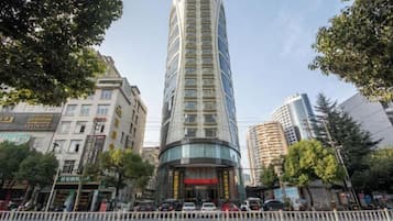 A tall, modern hotel with a curved facade, surrounded by other buildings and trees.