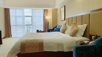 A hotel room with a large bed, a desk, a chair, and a window with curtains.