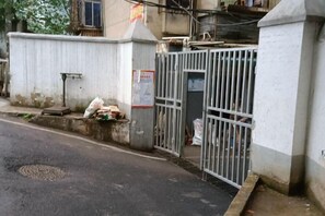 A gated entrance with a metal gate, a concrete wall, and a small step leading to a door. - Optics Valley Affordable Apartment (Wuhan)