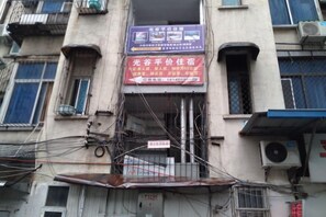 Un edificio de varios pisos, un cartel con texto y varias unidades de aire acondicionado.