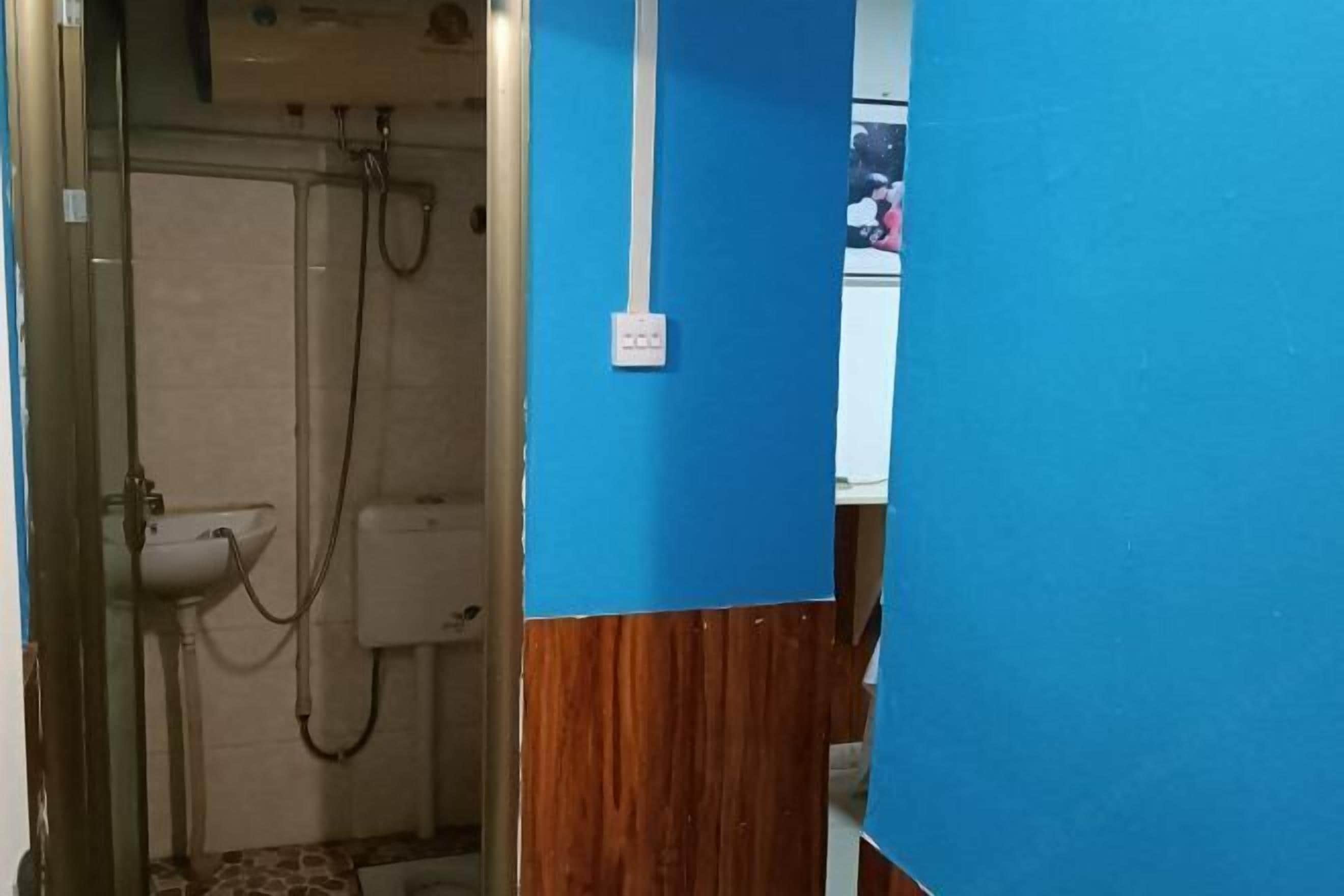 A bathroom with a shower, sink, and a visible electrical outlet on the wall.