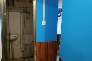Casa de banho com chuveiro, pia e uma tomada elétrica visível na parede.