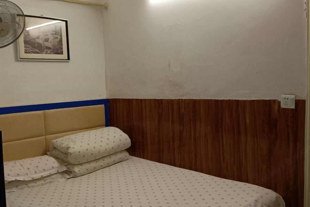 Quarto com cama, ventoinha na parede e quadro emoldurado.