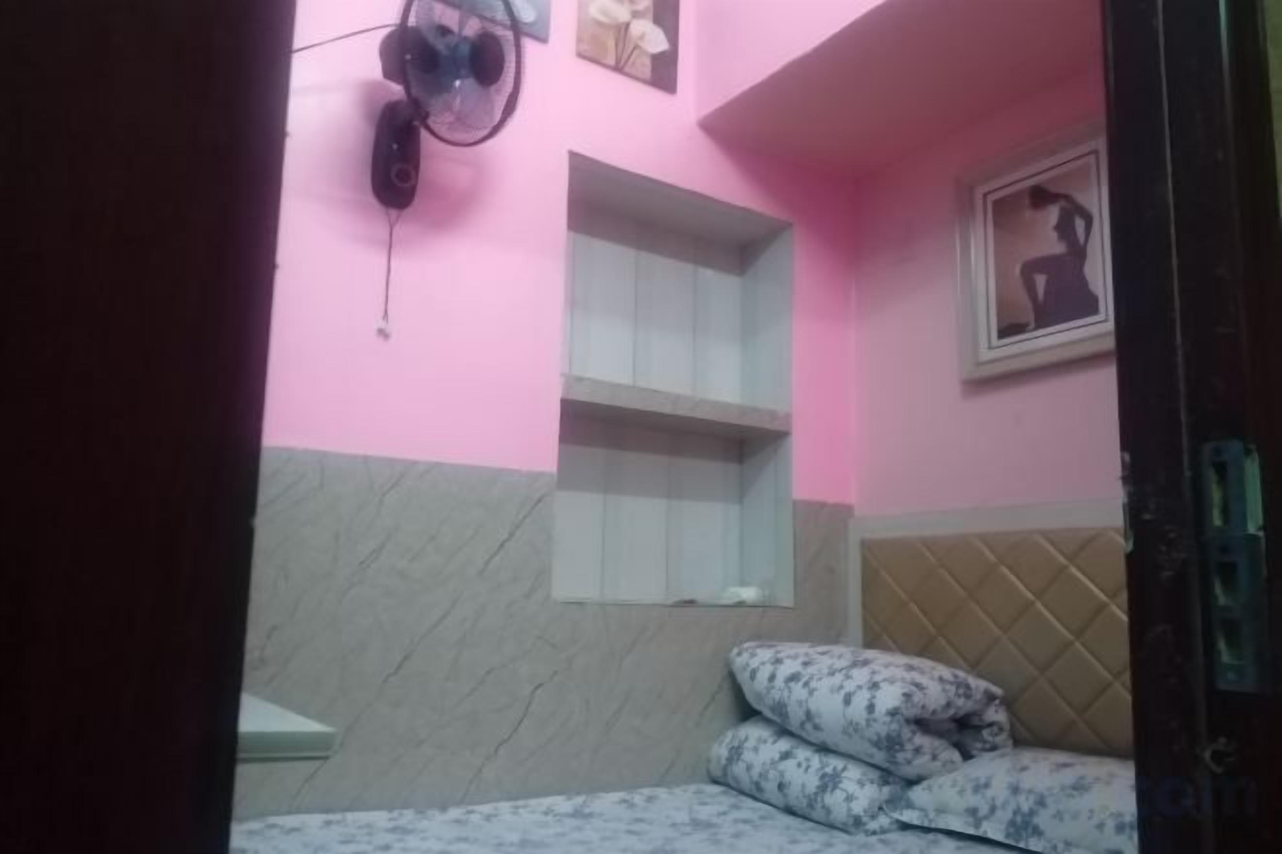 Een kamer met een bed, een wandplank en een fotolijst.