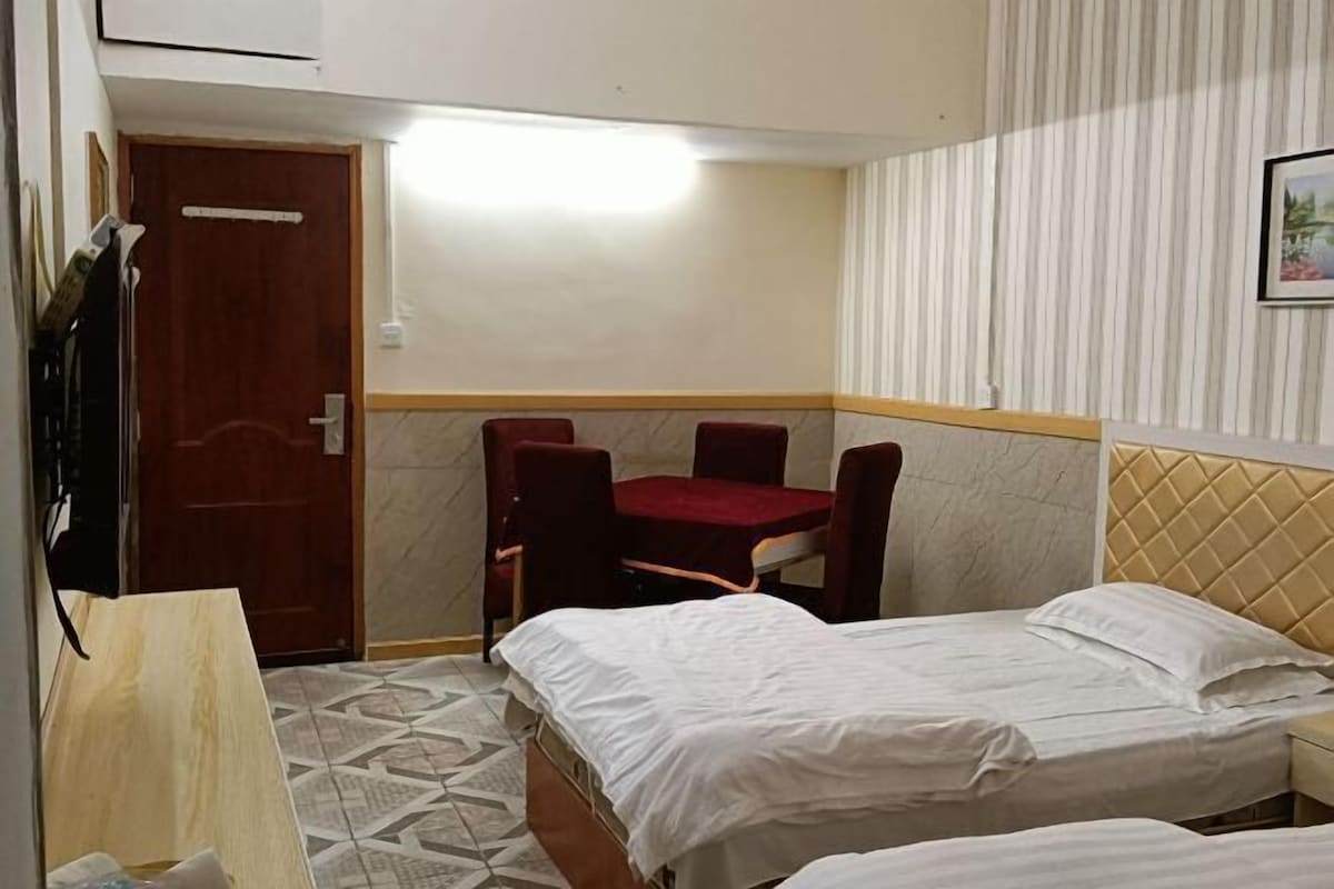 Quarto de hotel com duas camas, uma escrivaninha de madeira, uma cadeira e parede listrada.