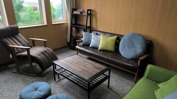 A living room with a brown leather sofa, a wooden coffee table, a green armchair, and two blue bean bag chairs.