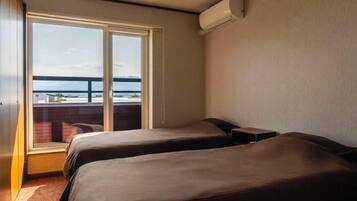 A hotel room with two beds, a large window, and an air conditioning unit.
