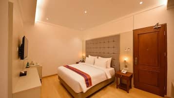 A hotel room with a bed, bedside tables, a TV, a wardrobe, and a door.