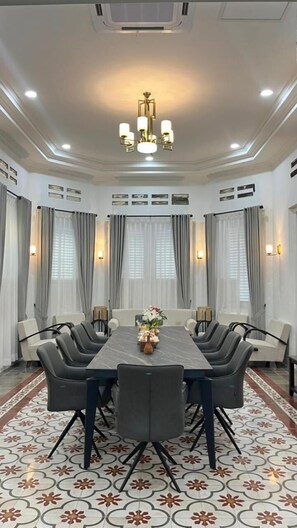 A conference room with a rectangular table, six chairs, a chandelier, and patterned flooring. - Khas Ombilin Hotel (Lembah Segar)