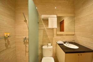 A modern bathroom with a glass shower enclosure, a toilet, a sink with a black countertop, and a mirror above the sink. - Khas Ombilin Hotel (Saringan)