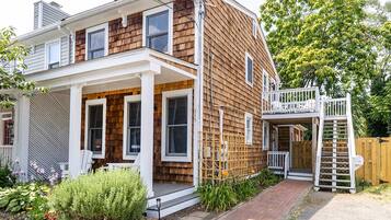 A two-story house with a wooden exterior, a covered porch, and a small deck.