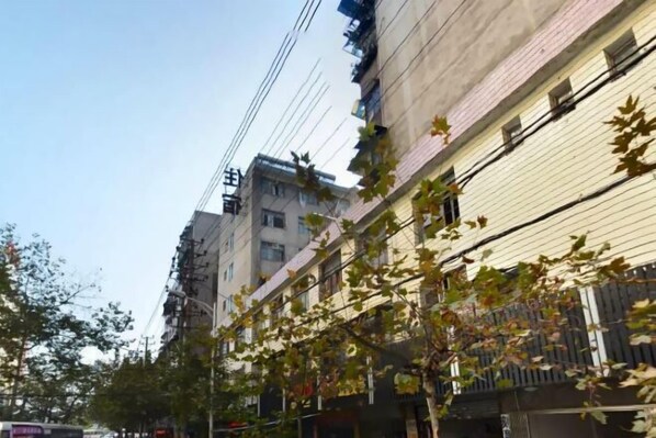 Vista de una calle con edificios de varios pisos, algunos con balcones y líneas eléctricas visibles.