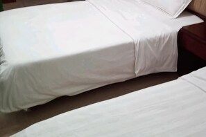 Een bed met een witte matras en een houten hoofdeinde.