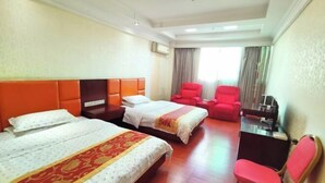 Una camera d'albergo con due letti, una scrivania, una sedia e una poltrona rossa.
