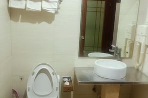 A bathroom with a toilet, sink, mirror, and towel rack.