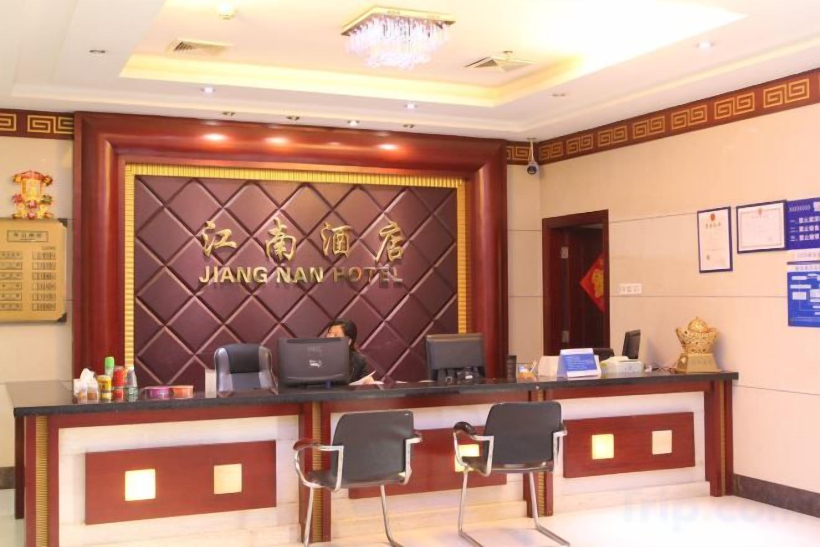 A reception desk with a sign reading 'JIANG NAN HOTEL' and a computer monitor. There are two chairs in front of the desk.