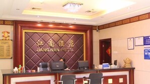 Una reception con una insegna che recita "Jiangnan Hotel" e due sedie nere di fronte.