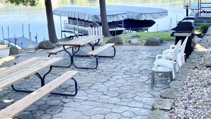 Een picknickplaats aan het meer met houten banken en picknicktafels, omgeven door een stenen pad.