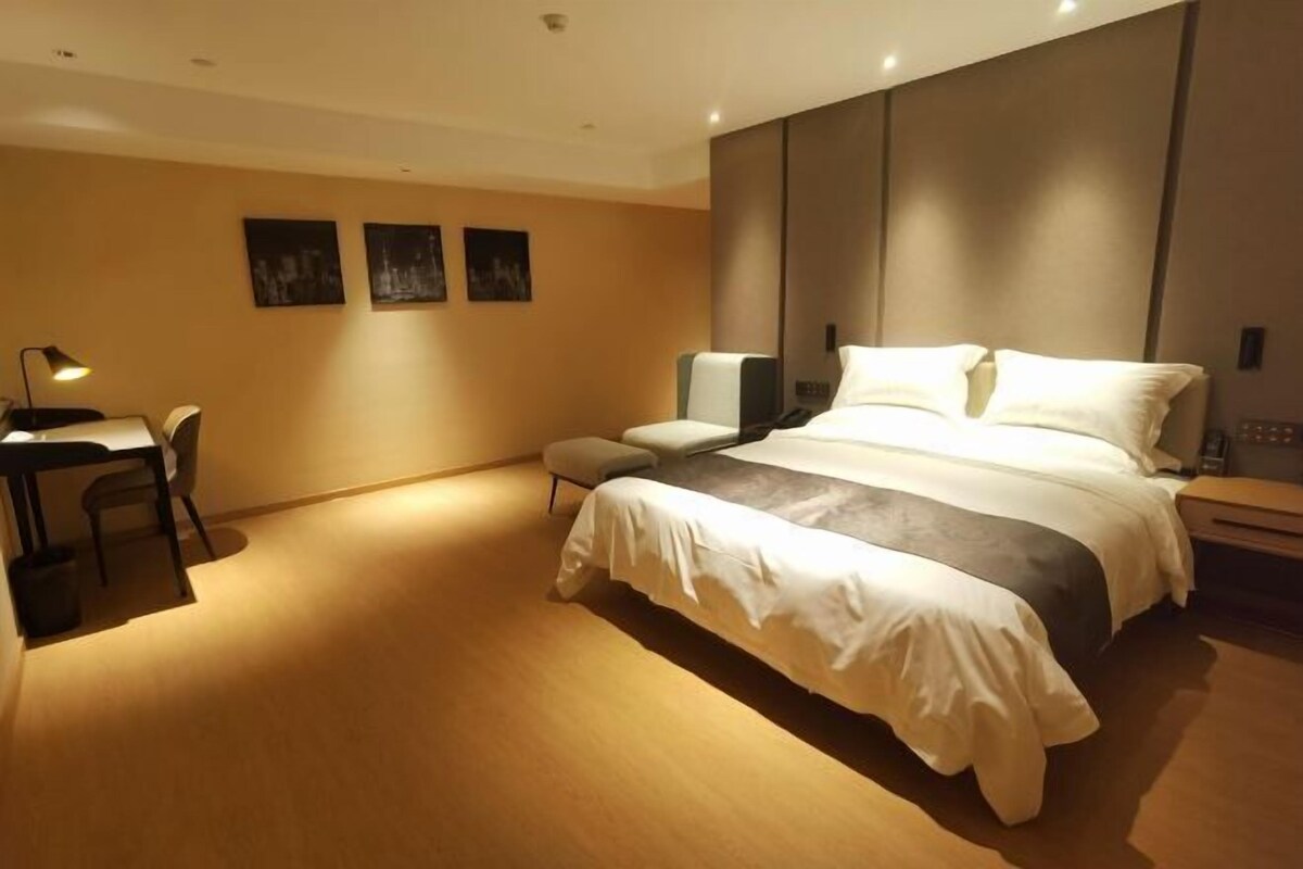 A modern hotel room with a large bed, a desk, and a chair.