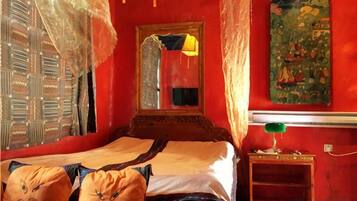 Une pièce avec un lit, un miroir, une lampe verte et un tableau mural.