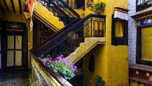 A staircase with ornate black railings and yellow walls, leading to an upper floor. - House of Shambhala Heritage Hotel (Lhasa)