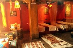 A room with two beds, a wooden floor, and a striped rug.