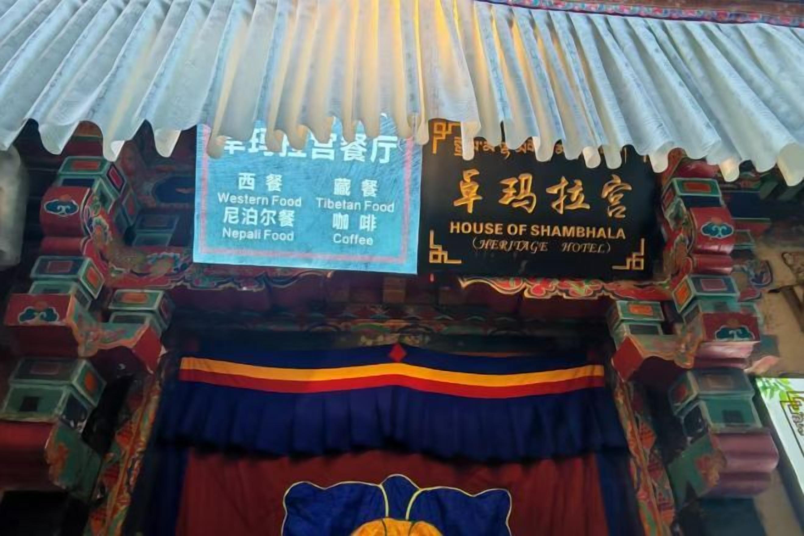 A traditional Tibetan-style building with signs indicating Western, Tibetan, and Nepalese food options, as well as a coffee shop.