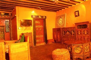 A room with a wooden ceiling, a large ornate door, and a traditional cabinet. - House of Shambhala Heritage Hotel (Lhasa)