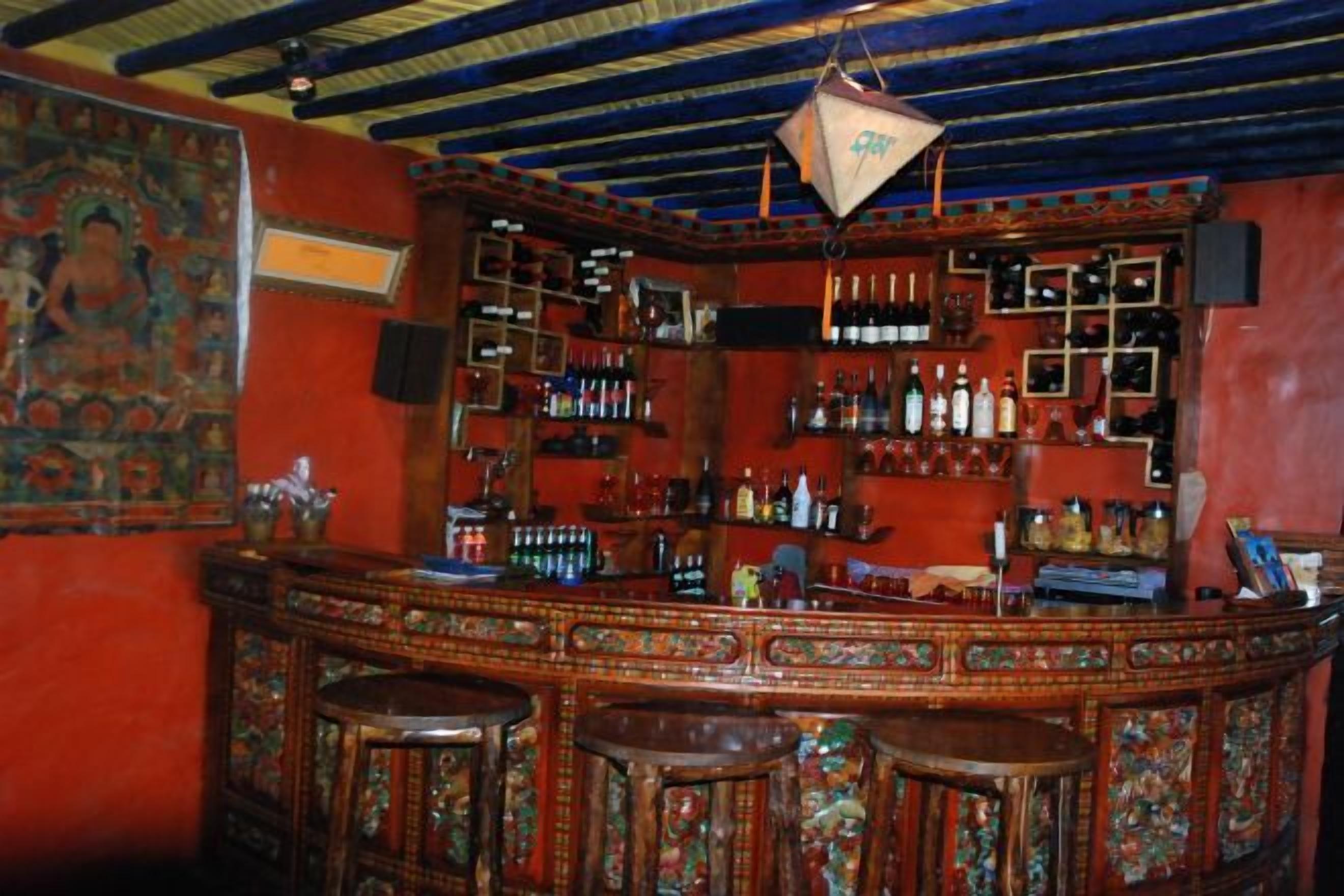 Un bar avec un comptoir en bois, de nombreux tabourets et des étagères remplies de bouteilles.