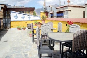 An outdoor patio with wicker furniture and potted plants. - House of Shambhala Heritage Hotel (Lhasa)