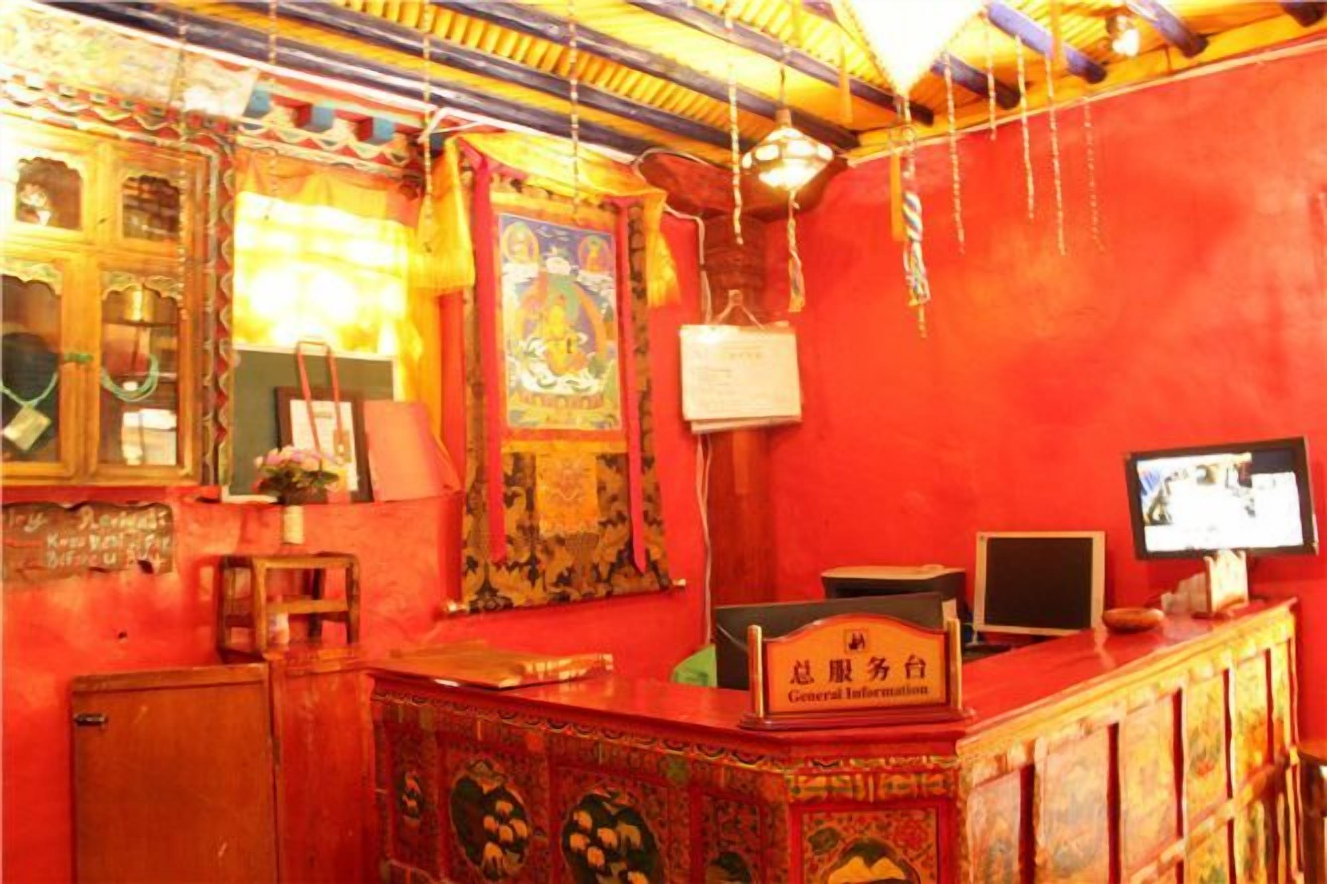 Une pièce avec un mur rouge, un meuble en bois, un bureau avec un ordinateur et un téléviseur.