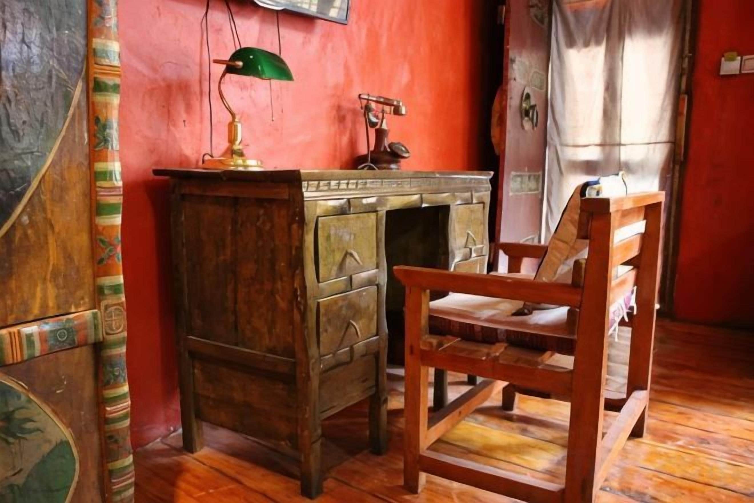 Una habitación con un escritorio de madera, una silla y una lámpara.