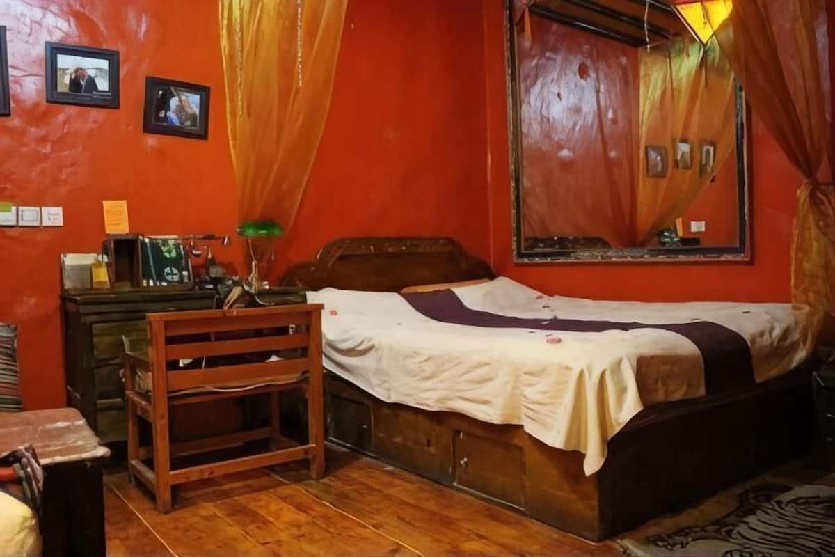 A room with a bed, a desk, a chair, a mirror, and curtains.