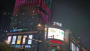 Een gebouw met verlichte verticale lijnen en een grote reclamebord.