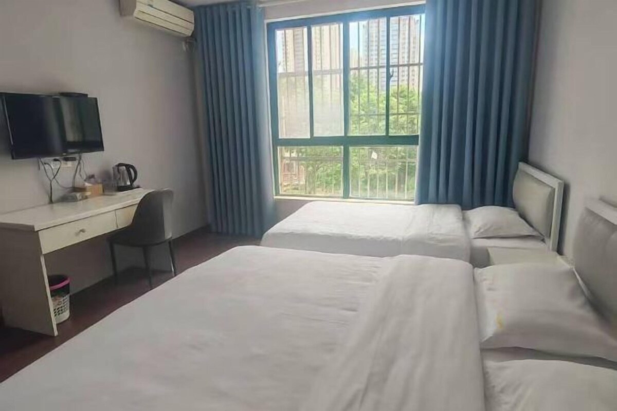 Habitación de hotel con dos camas, un escritorio, una silla, un televisor y una ventana con cortinas.