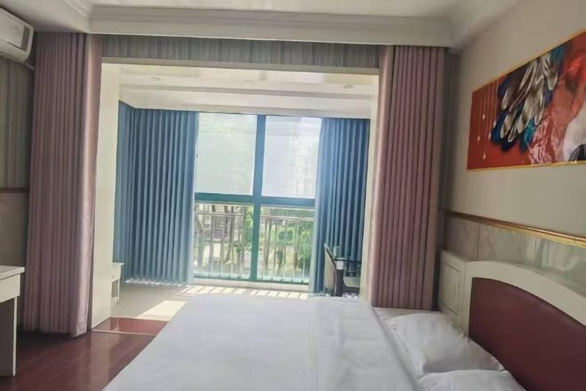 Una habitación de hotel con cama, escritorio y balcón con cortinas.