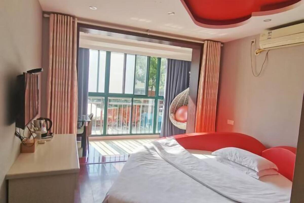 Een moderne hotelkamer met een groot bed, een televisie en een balkon met gordijnen.