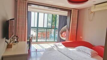 A modern hotel room with a large bed, a television, and a balcony with curtains.