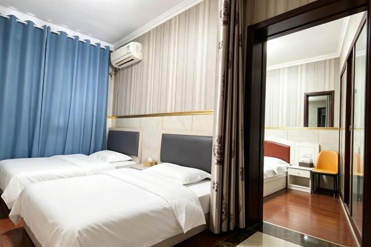 Une chambre d’hôtel avec deux lits, un bureau et une chaise.