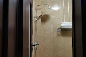 Une salle de bain avec une douche, un porte-serviettes et une porte.