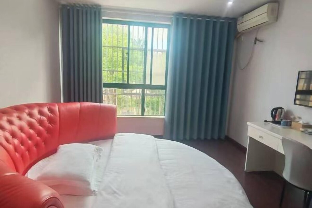 Una habitación de hotel con una cama, un escritorio y un ventanal con cortinas.