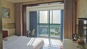 A hotel room with a bed, a desk, a chair, and a balcony with curtains. - Yancheng Xinyue Theme Hotel (Jiangsu Vocational College of Medicine Kangleyuan Branch) (Yancheng)