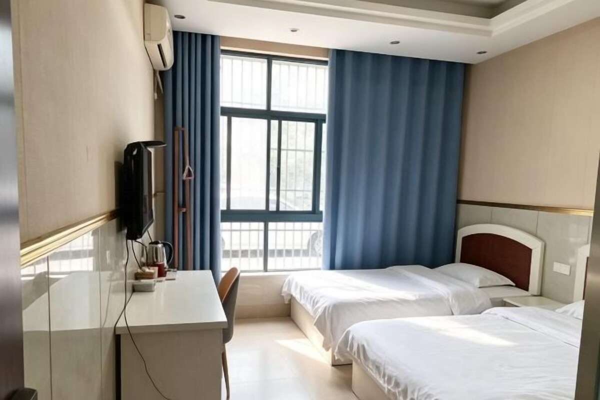 Une chambre d’hôtel avec deux lits, un bureau et une télévision.