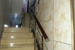 Una escalera de mármol con barandillas de metal que sube a un piso superior.